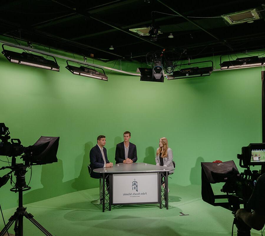 Sports broadcasting students present in front of a green screen.